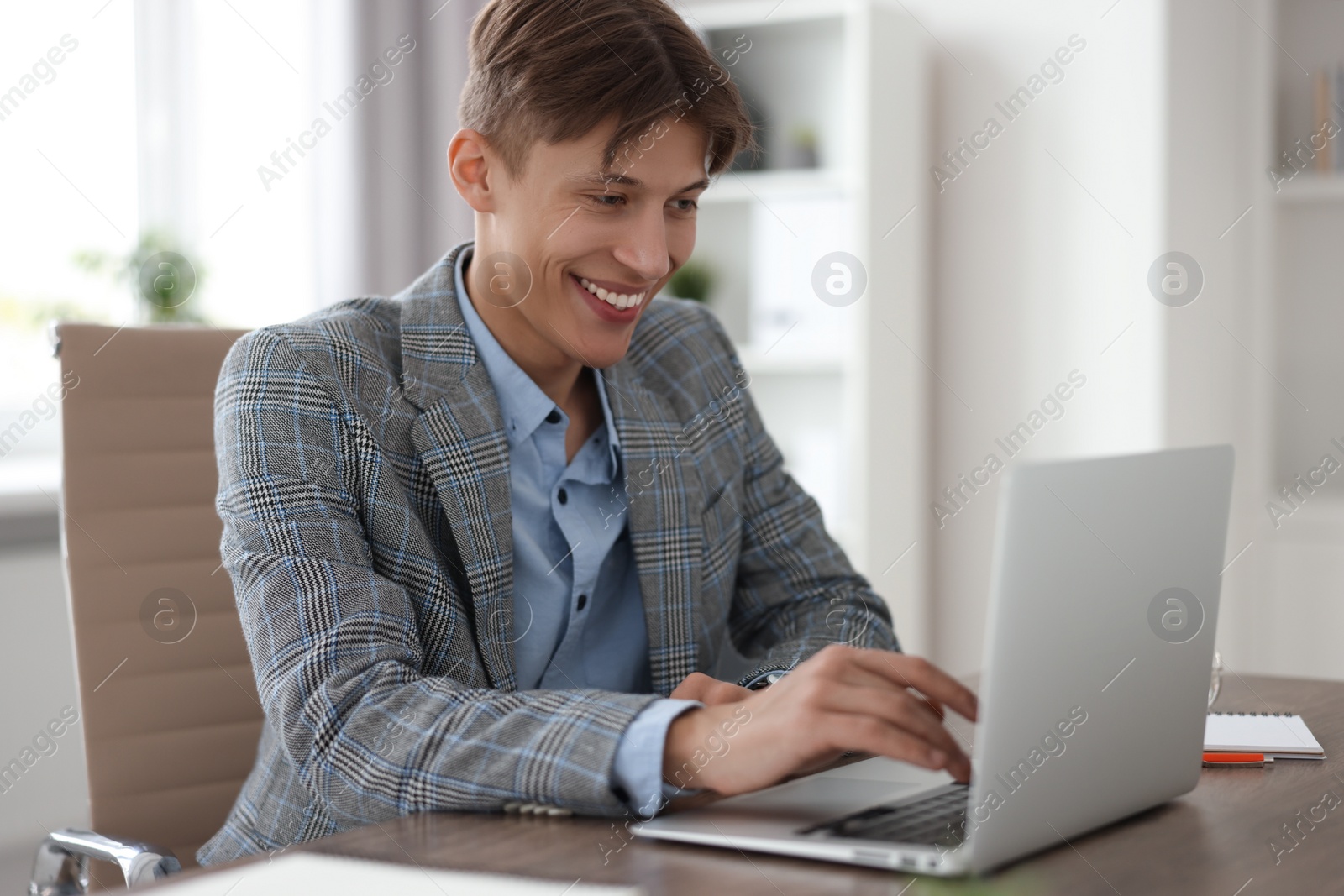 Photo of Man watching webinar at wooden table in office