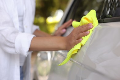 Photo of Woman cleaning car with rag outdoors, closeup view