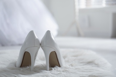 Photo of White wedding shoes on furry rug in room, back view. Space for text