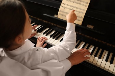 Young woman with child playing piano, closeup. Music lesson