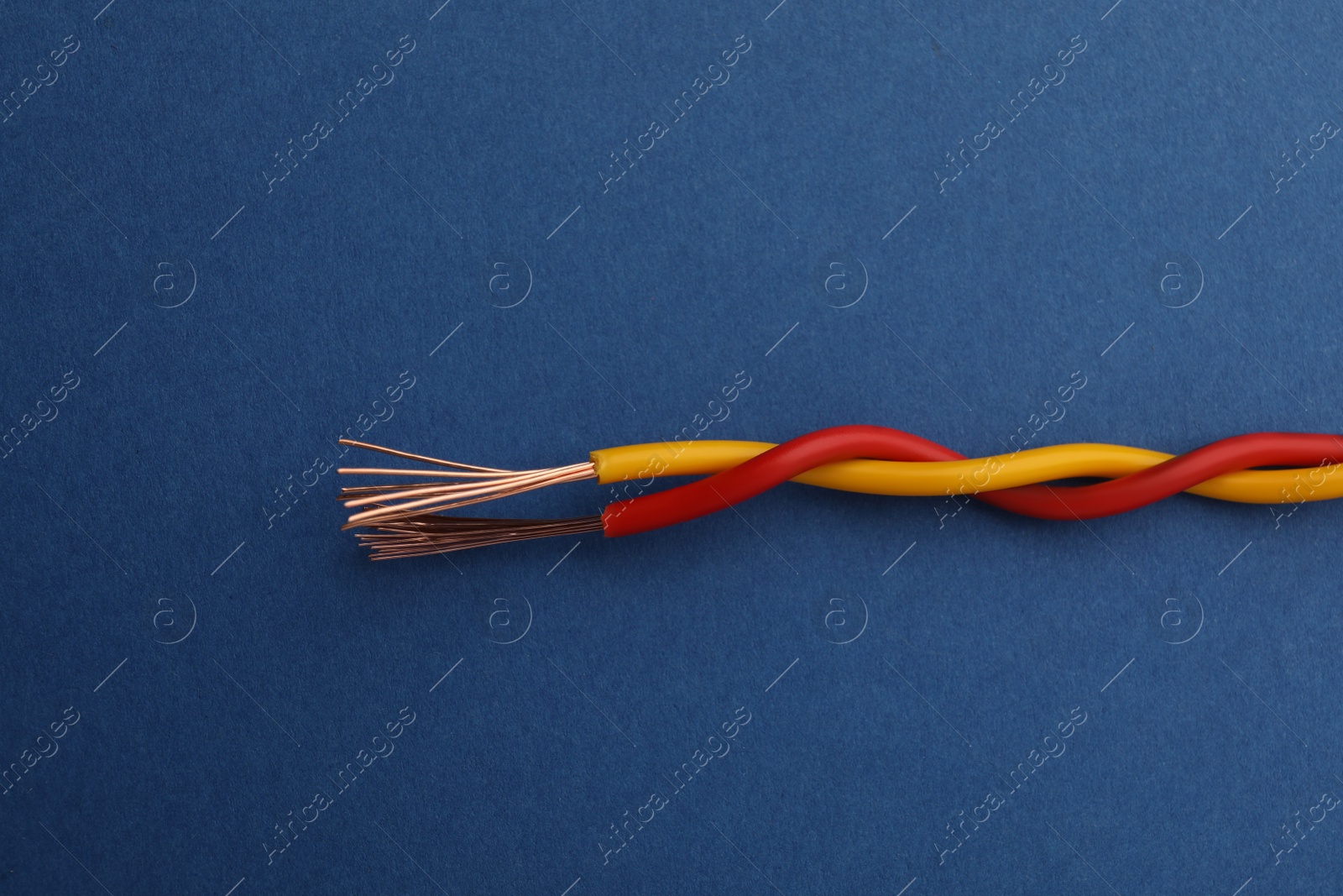 Photo of Two twisted electrical wires on blue background, closeup