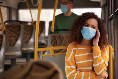 Photo of African-American woman with disposable mask on bus. Virus protection