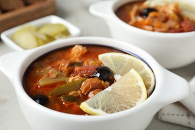 Meat solyanka soup with sausages, olives and vegetables on white table, closeup