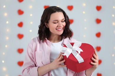 Beautiful young woman with gift box indoors, view from camera. Valentine's day celebration in long distance relationship