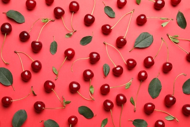 Photo of Tasty ripe cherries with leaves on red background, flat lay