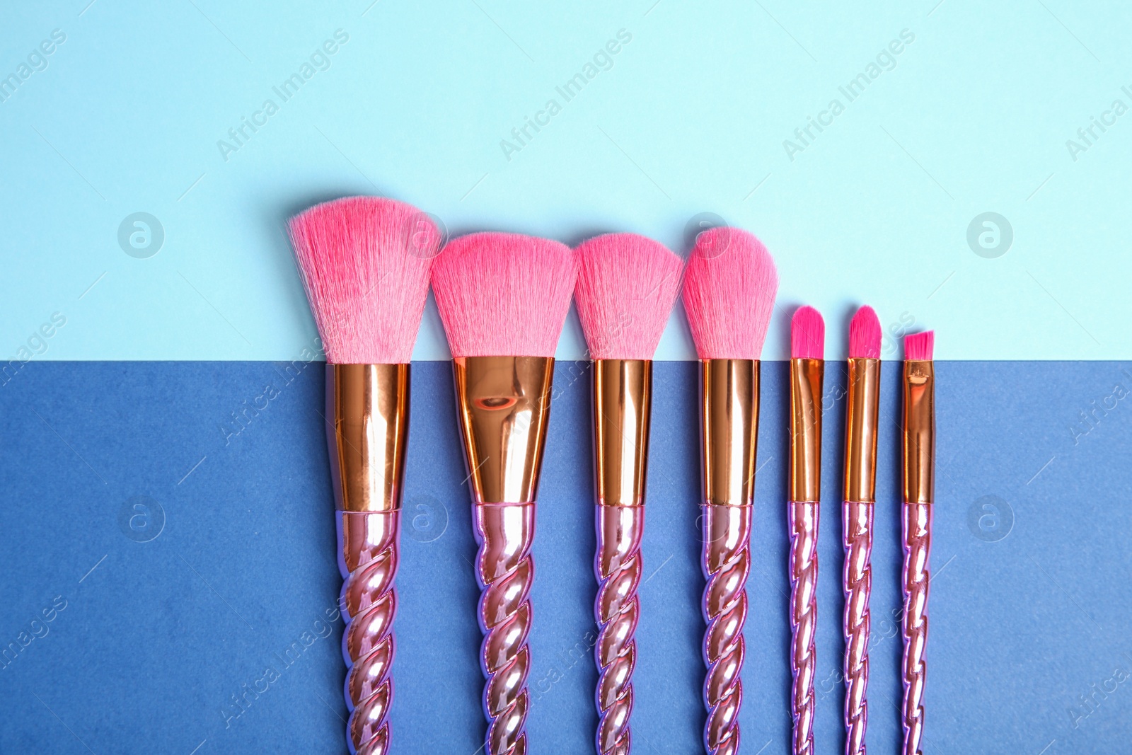 Photo of Flat lay composition with set of professional makeup brushes on color background