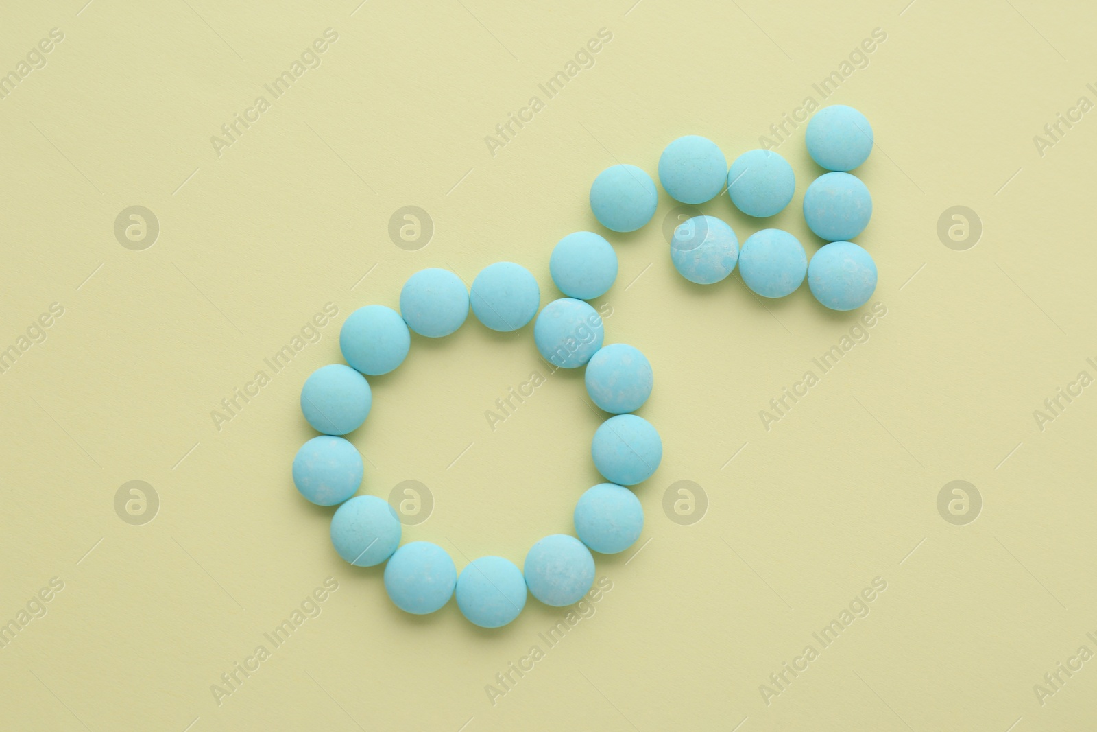 Photo of Male sign with bent arrow of blue pills symbolizing potency problems on beige background, flat lay