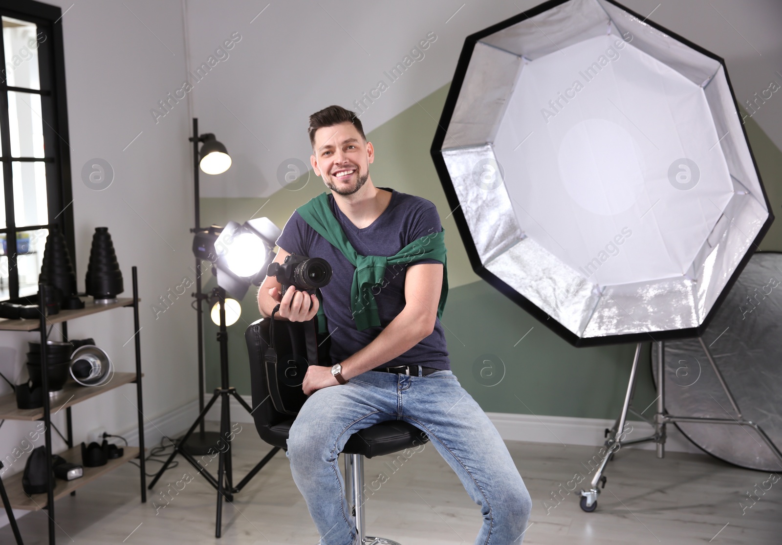 Photo of Professional photographer with camera and lighting equipment in studio