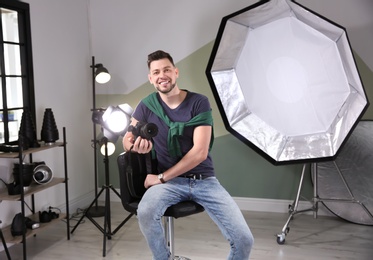 Photo of Professional photographer with camera and lighting equipment in studio