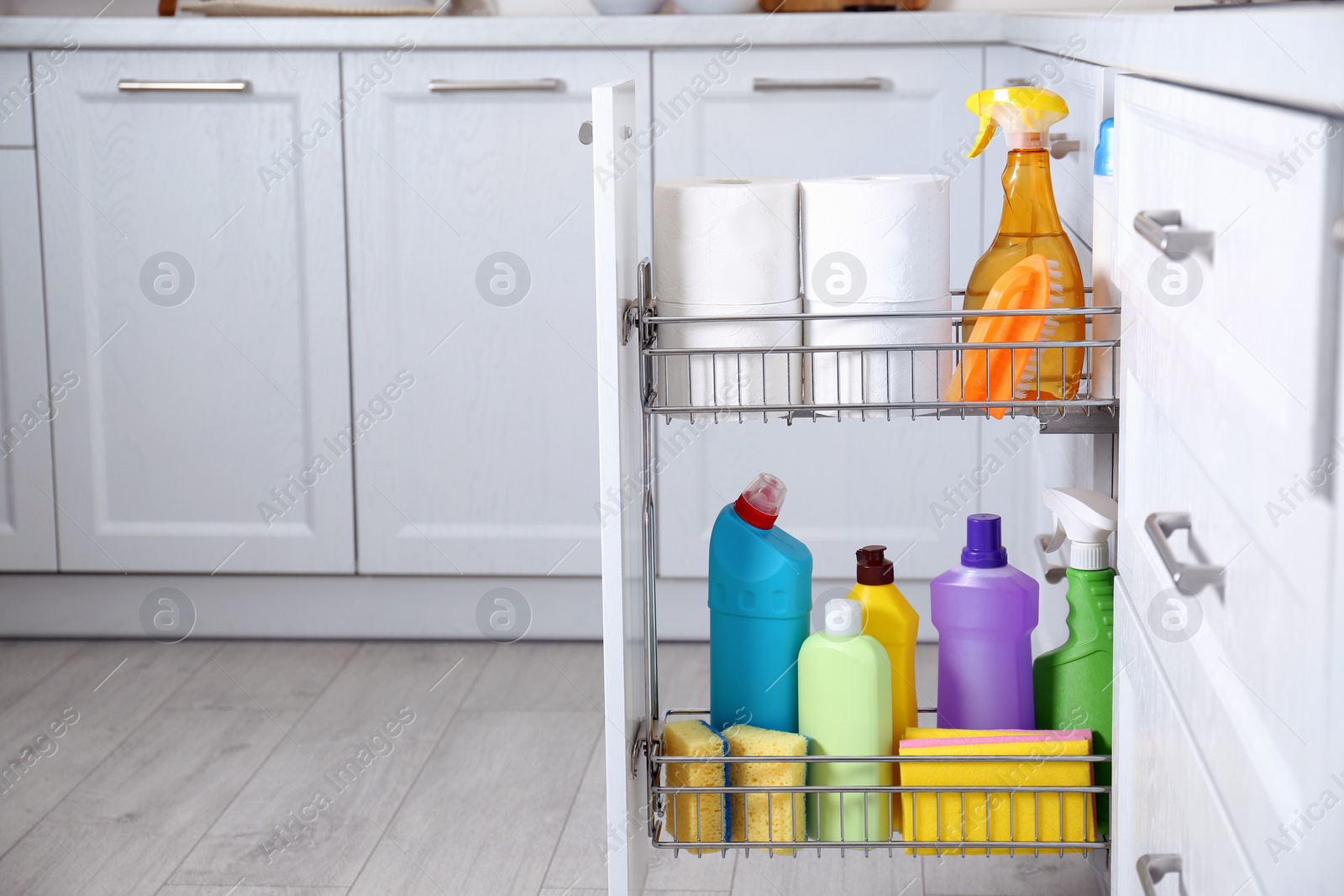 Photo of Open drawer with different cleaning supplies in kitchen, space for text