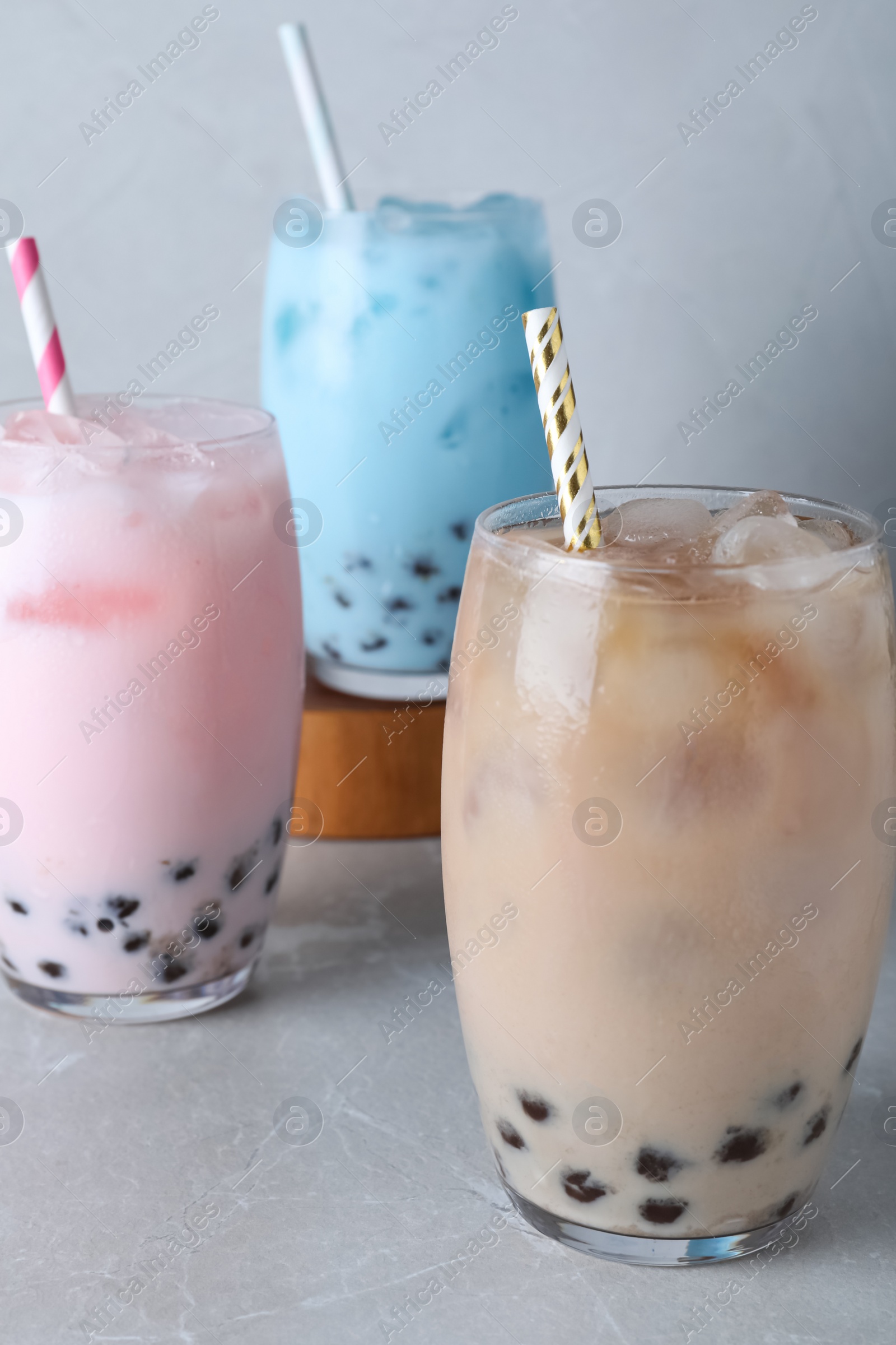 Photo of Different milk bubble teas on light grey table