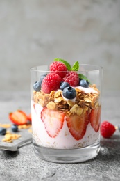 Photo of Glass of tasty homemade granola dessert on grey table. Healthy breakfast