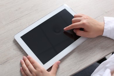 Photo of Woman using tablet at wooden table, closeup