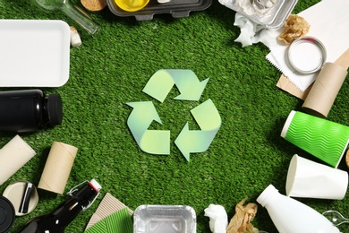 Photo of Recycling symbol and different garbage on synthetic turf