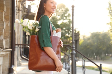 Woman with leather shopper bag near building