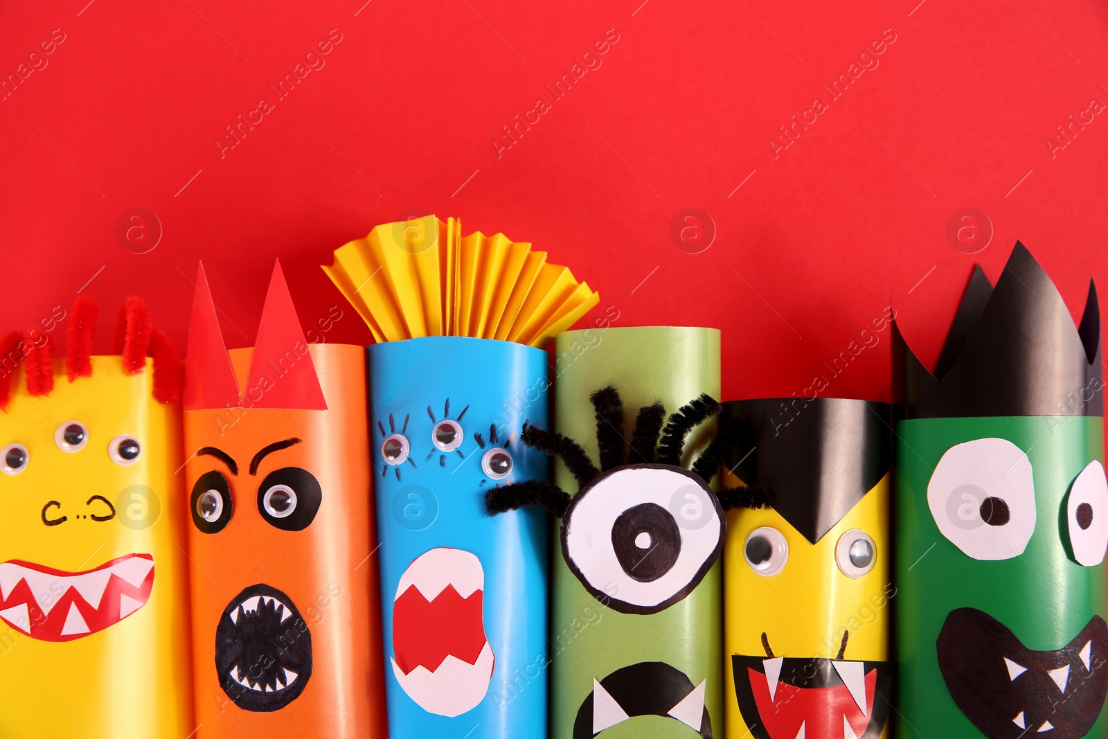 Photo of Funny monsters on red background, flat lay. Halloween decoration