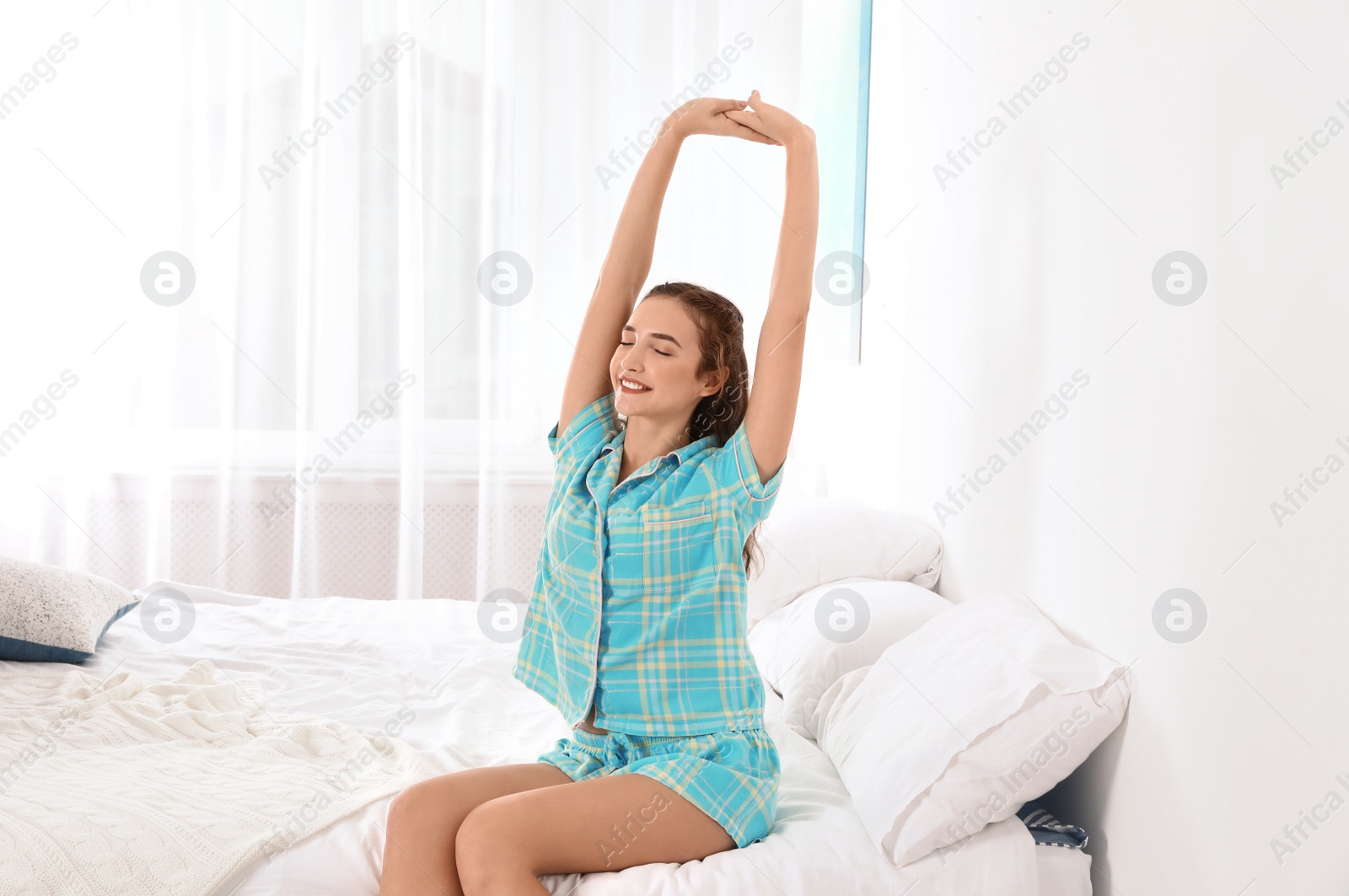 Photo of Young woman stretching on bed at home. Morning fitness