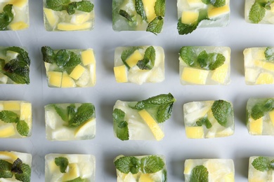 Photo of Ice cubes with mint and lemon on light background, top view