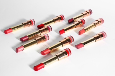 Photo of Set of bright lipsticks in gold tubes on white background