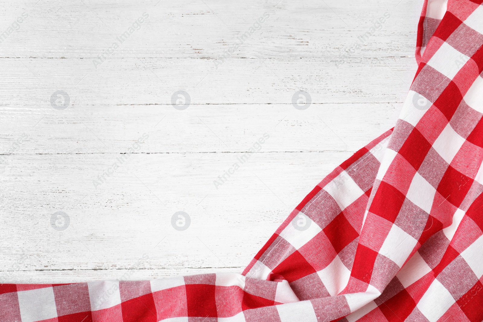 Photo of Checkered picnic blanket on wooden background, top view. Space for text