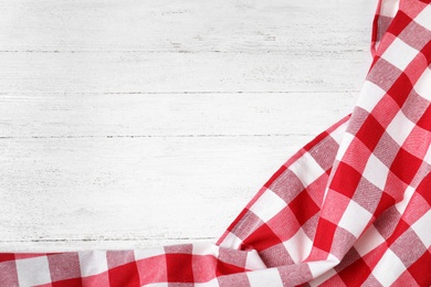 Checkered picnic blanket on wooden background, top view. Space for text