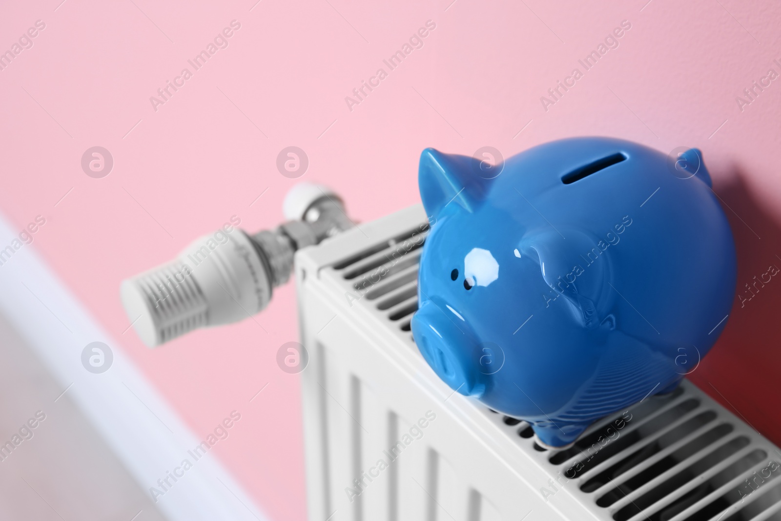Photo of Heating radiator with piggy bank near color wall