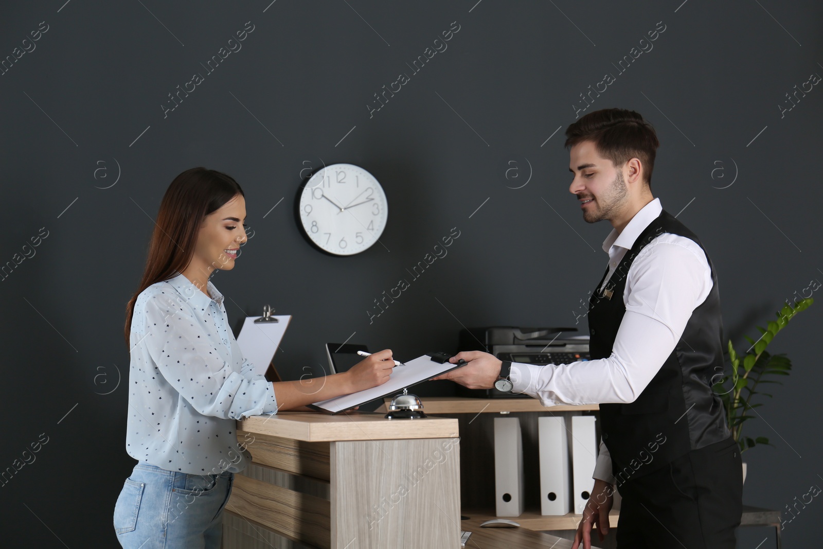 Photo of Receptionist registering client at desk in lobby