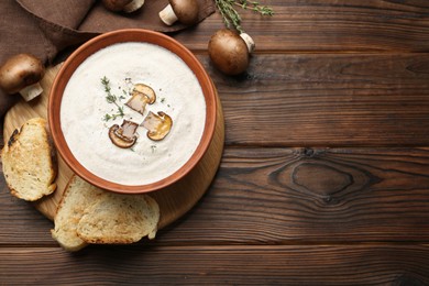 Fresh homemade mushroom soup in ceramic bowl on wooden table, flat lay. Space for text