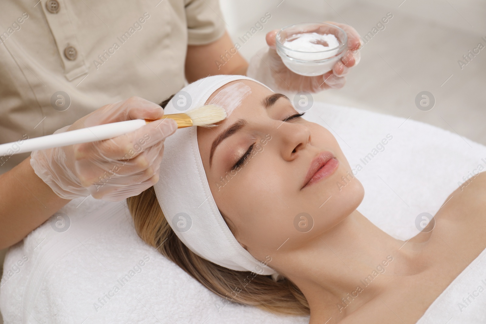 Photo of Young woman during face peeling procedure in salon