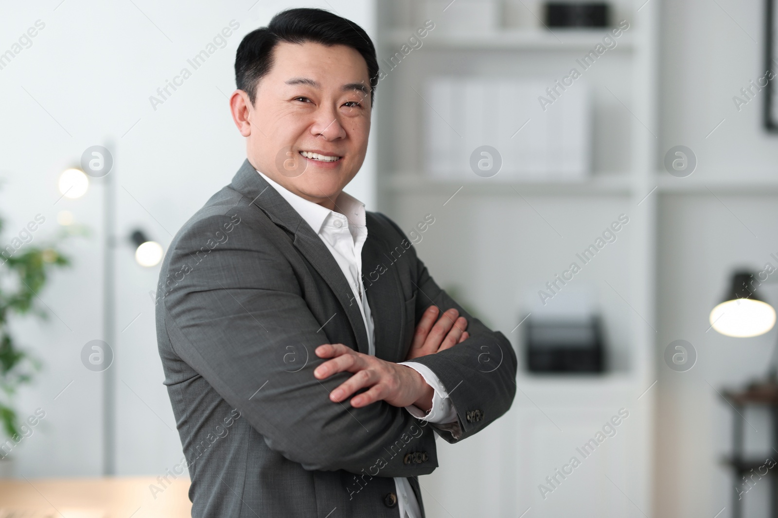 Photo of Portrait of smiling businessman with crossed arms in office. Space for text