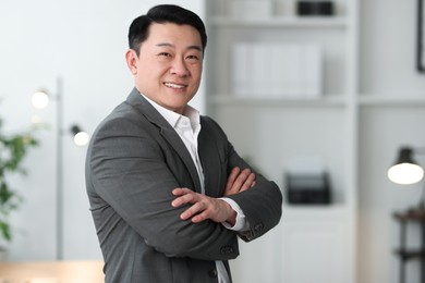 Portrait of smiling businessman with crossed arms in office. Space for text