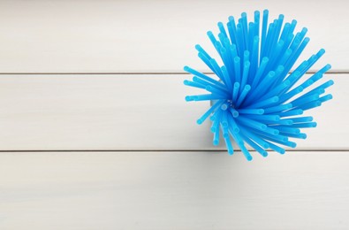 Photo of Light blue plastic drinking straws on white wooden table, top view. Space for text