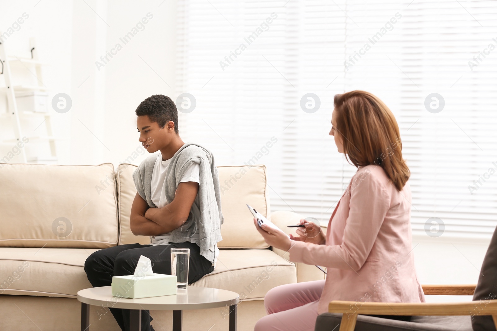 Photo of Psychotherapist working with teenage African-American boy in office