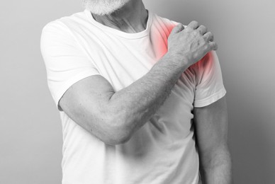 Man suffering from pain in shoulder, closeup. Black and white effect