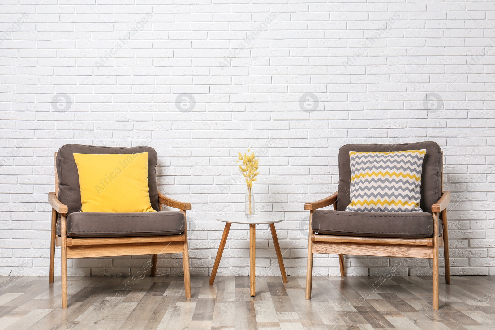 Photo of Room interior with modern armchairs and table near white brick wall