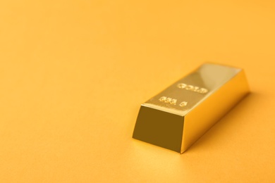 Photo of Precious shiny gold bar on color background. Space for text