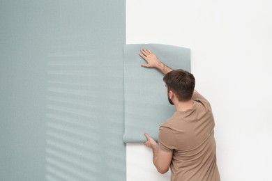 Photo of Man hanging stylish wall paper sheet. Space for text
