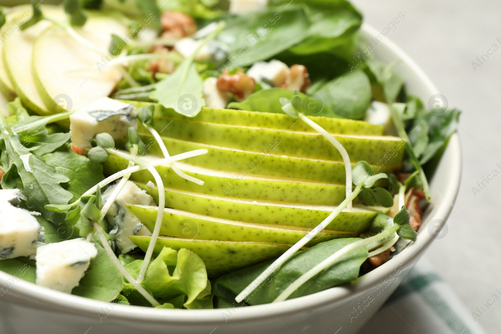 Photo of Tasty salad with pear slices in bowl, closeup