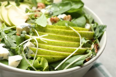 Tasty salad with pear slices in bowl, closeup