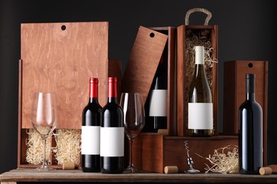 Different bottles of wine, glasses, wooden boxes, corks and corkscrew on table