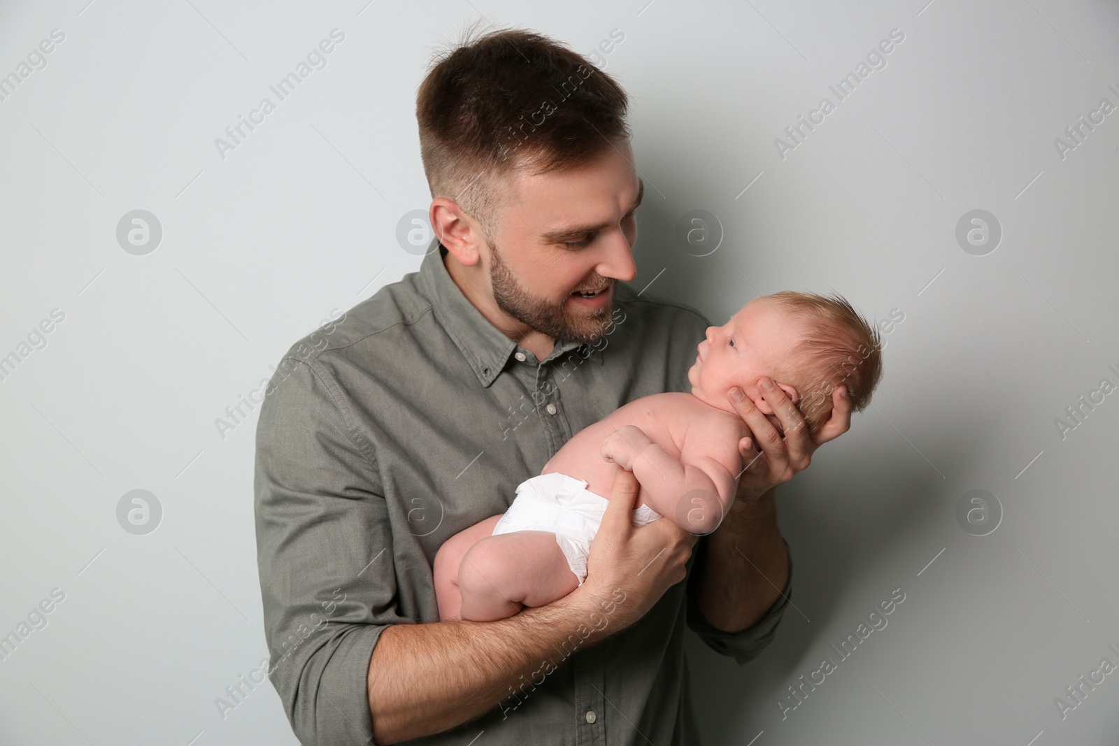 Photo of Father with his newborn son on light grey background