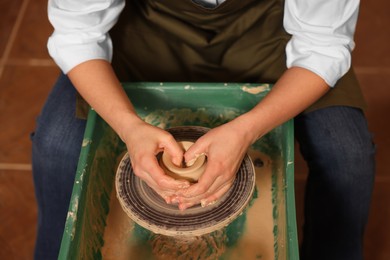 Woman crafting with clay on potter's wheel, closeup