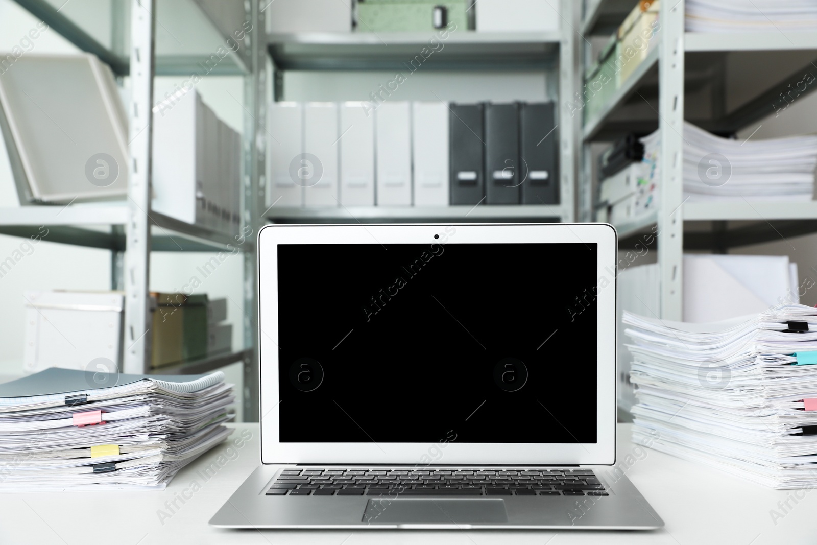 Photo of Laptop and documents on desk in office. Space for text