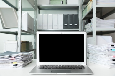 Laptop and documents on desk in office. Space for text