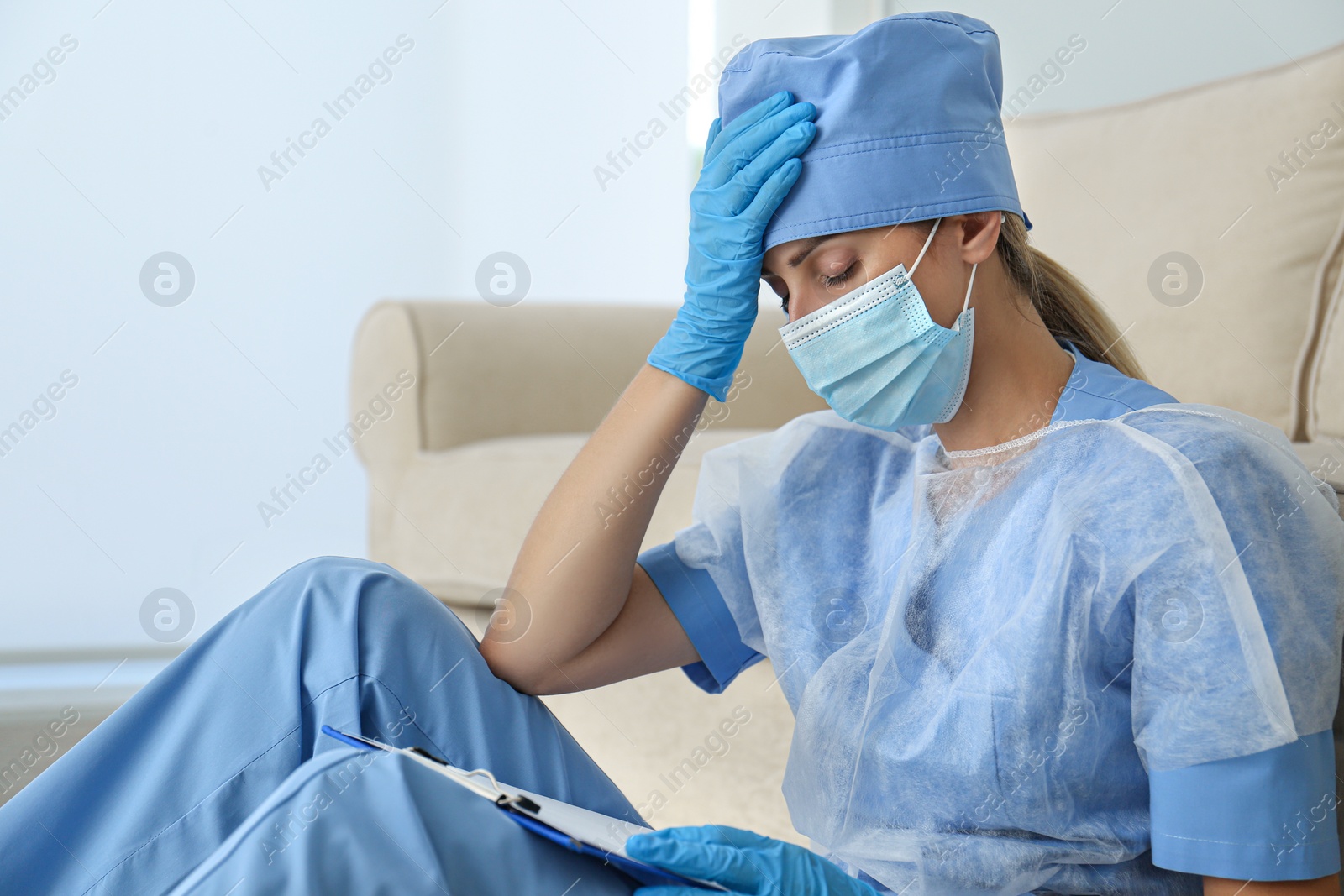 Photo of Exhausted doctor indoors. Stress of health care workers during COVID-19 pandemic