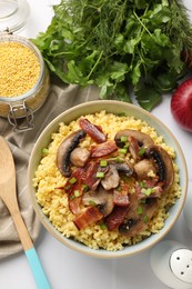 Photo of Tasty millet porridge with mushrooms, bacon and green onion in bowl on white table, flat lay