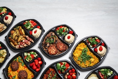 Photo of Lunchboxes with different meals on white table, flat lay. Healthy food delivery