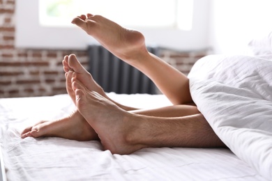 Photo of Passionate young couple having sex on bed at home, closeup of legs