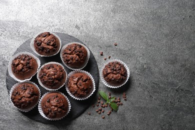 Photo of Tasty chocolate muffins on grey textured table, flat lay. Space for text