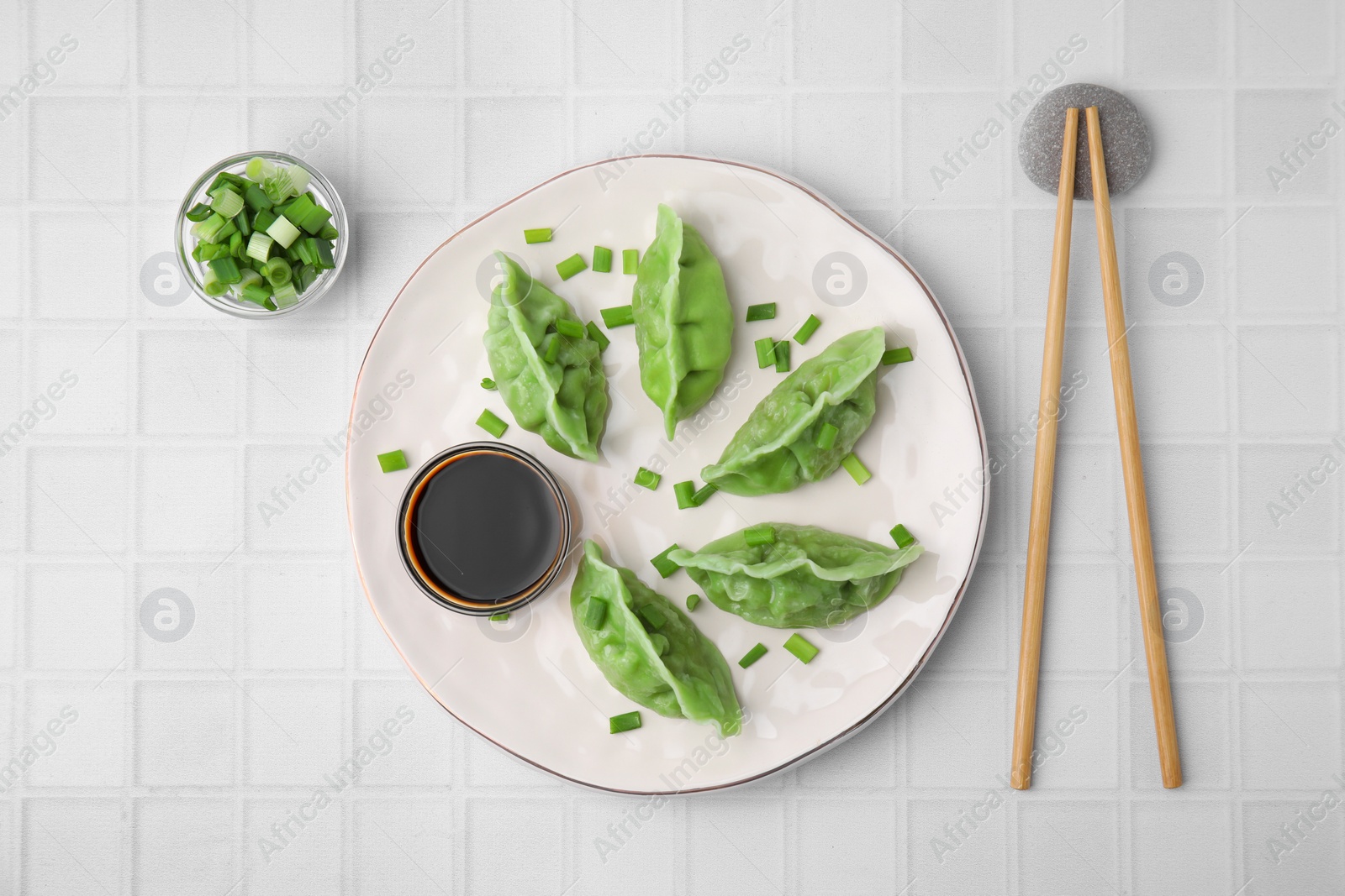 Photo of Delicious green dumplings (gyozas) served on white tiled table, flat lay